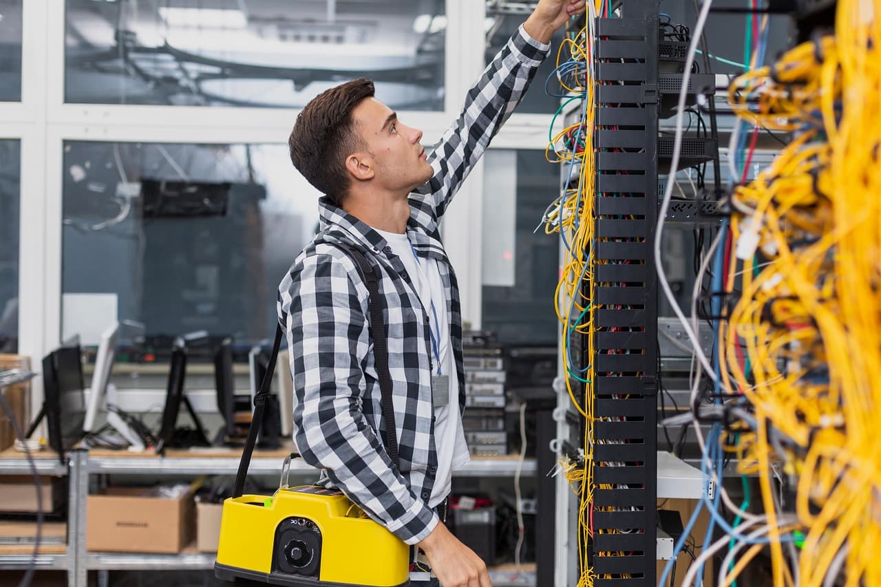 Technician installing structured cabling in a commercial network rack